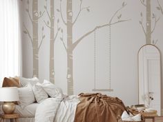 a bed room with a neatly made bed and a tree wall mural on the wall