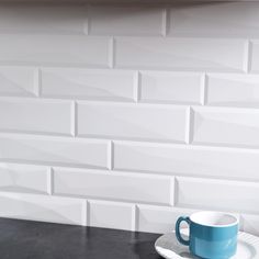 a blue coffee cup sitting on top of a saucer next to a white brick wall