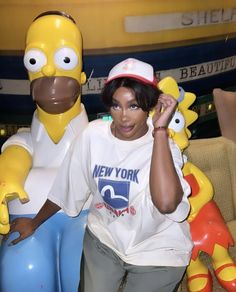 a woman sitting on top of a couch next to a statue of homer the simpsons