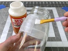 someone is painting the inside of a glass jar with glue and a toothbrush in it