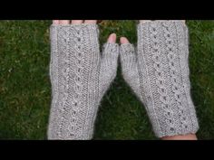 two hands with knitted mitts in front of green grass