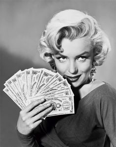 marilyn monroe holding money in one hand and looking at the camera with an expression on her face