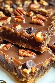 several pieces of chocolate pecan bars stacked on top of each other with nuts in them