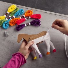 a person is holding a string and making a horse out of yarn on a table