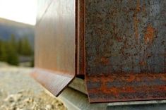 an old rusted metal box sitting on the side of a road with mountains in the background