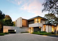 a modern house with large windows and brick driveway