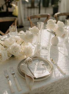 the table is set with white flowers and silverware