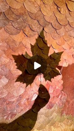 the shadow of a person holding a leaf in front of a colorful wall with leaves on it