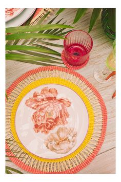 a plate with flowers painted on it sitting on a table next to a glass vase