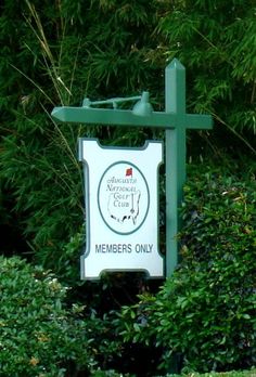 a sign in front of some bushes and trees with the words members only on it