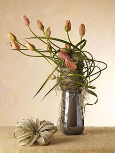 a vase filled with flowers sitting on top of a table next to an air plant