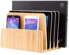 four cell phones are sitting in a wooden charging station with multiple compartments for their phones