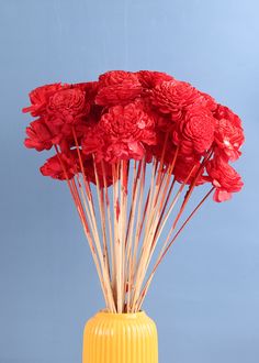 a yellow vase filled with red flowers on top of a table