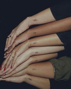 four women with matching tattoos on their arms and hands are stacked up in the air