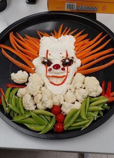 a plate that has some vegetables in it and a clown face painted on the side