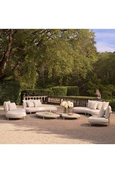 an outdoor seating area with white furniture and flowers on the table in front of it