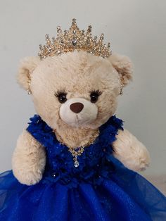 a teddy bear wearing a blue dress with a tiara on it's head