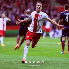 a soccer player is running on the field with his arms out and one foot in the air