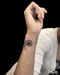 a woman's arm with a small tattoo on the wrist and a spiral design