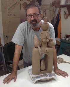 a man standing next to a clay sculpture