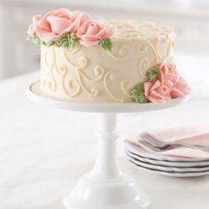 a white cake sitting on top of a table next to a plate and silverware