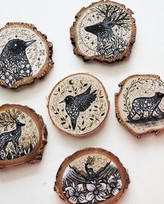 four wood slices with designs on them sitting on a white table top next to each other