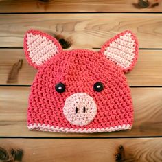 a crocheted pig hat on top of a wooden table next to wood planks