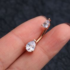 a pair of diamond earrings sitting on top of someone's finger