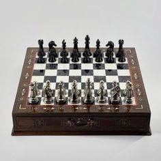 the chess board is made out of wood and has metal pieces on it, including black and white figures