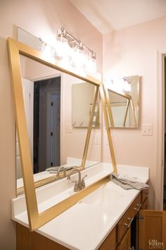 a bathroom with a mirror, sink and lights on the wall above it's mirrors