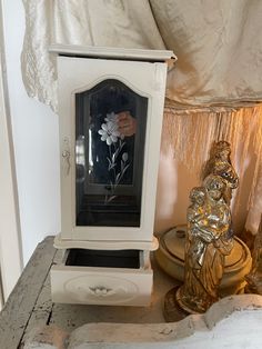 a white clock sitting on top of a wooden table next to a gold figurine