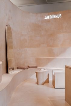 the interior of a bathroom with white walls and beige flooring, including an oval shaped mirror