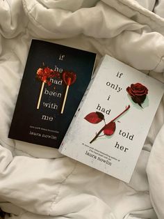 two books laying on top of a bed next to each other, one is red and the other is black