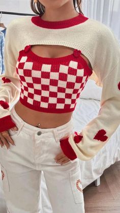 a woman standing in front of a bed wearing white jeans and a red checkered sweater