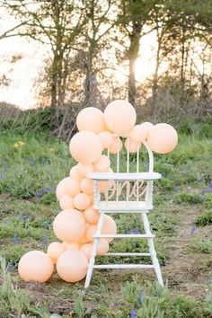 a chair with balloons attached to it sitting in the grass