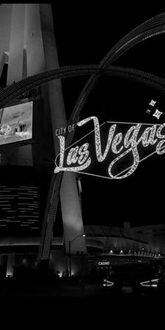 the las vegas sign is lit up in black and white at night with city lights