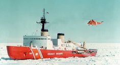 a helicopter flying over a red boat in the ocean with snow on the ground and ice floes