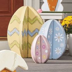 three painted eggs sitting on the ground next to flowers and a potted planter