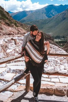 a man carrying a woman on his back in the mountains