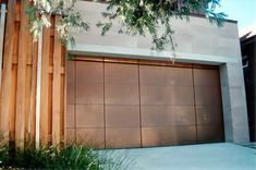 a brown garage door sitting in front of a tall wooden structure with trees growing out of it