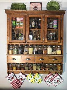 a wooden cabinet filled with lots of jars and spices next to a wall mounted spice rack