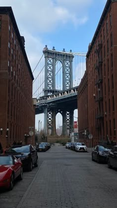 cars are parked on the street in front of tall buildings with a bridge above them