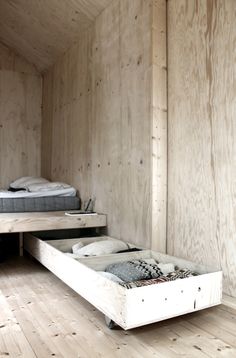 a bed sitting in the middle of a room next to a wooden wall and floor