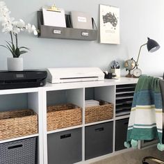 a desk with some baskets on it and a printer in the corner next to it