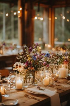 wooden table decorated with candles in mason jars and wildflowers Fairy Garden Themed Wedding, Fairy Wedding Ideas Decor, Fairy Lights And Flowers Wedding, Floral Fairy Wedding, Classy Wildflower Wedding, Summer Fairy Wedding, Cozy Summer Wedding, Fairy Garden Theme Wedding, Wildflower And Candle Centerpieces