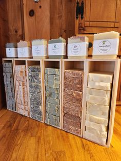 several different types of soaps are on display in a wooden cabinet with labels for each one