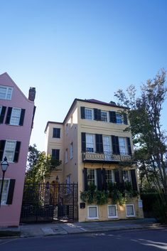 two buildings with windows and balconies on the second floor are painted pink, while another one has black shutters