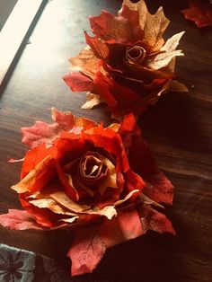 two paper flowers sitting on top of a wooden table