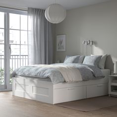 a white bed sitting next to a window in a bedroom