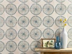 a blue vase sitting on top of a wooden table next to a wallpaper covered in circles